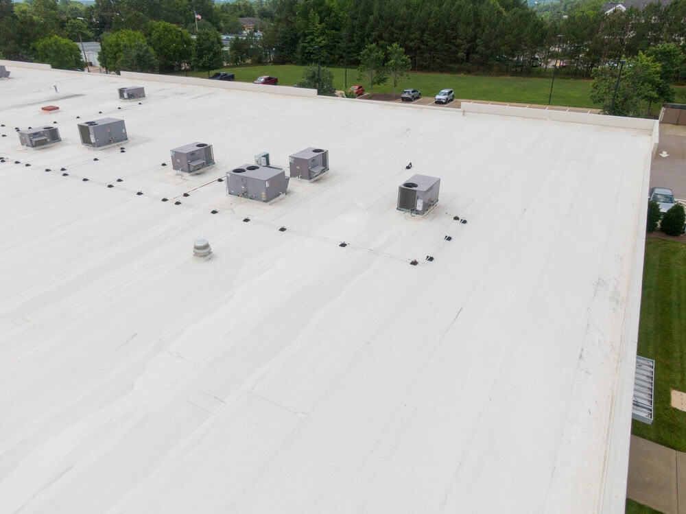 A white single-ply commercial roofing system with HVAC equipment